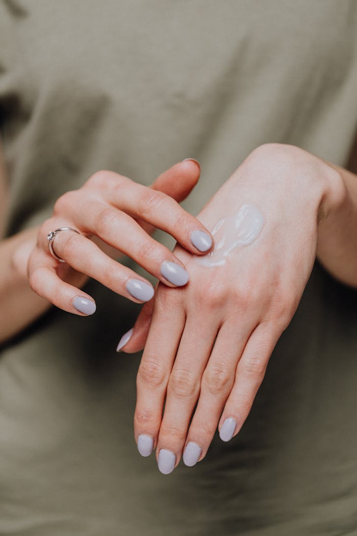 gallery-02 Close-up of female hands applying moisturizer cream for smooth skin care.